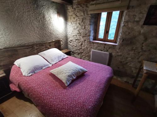 a bedroom with a large bed with purple sheets and pillows at Les Citounelles in Citou