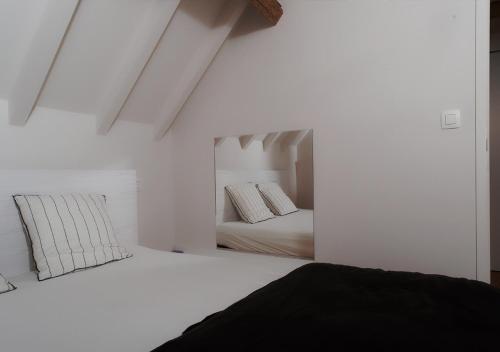 a white bedroom with two beds and a mirror at Gîte de l'Étang in Frasnes-lez-Anvaing