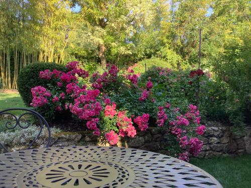 a table and bench in a garden with flowers at Toute Une Histoire près de Fontainebleau in Veneux-les-Sablons