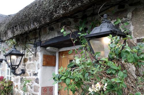 ein altes Steinhaus mit einer Lampe und einer Tür in der Unterkunft Bearslake Inn in Bridestowe