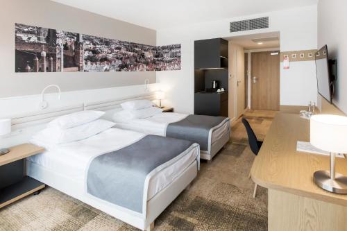 a hotel room with two beds and a desk at Hotel Platan in Gdańsk