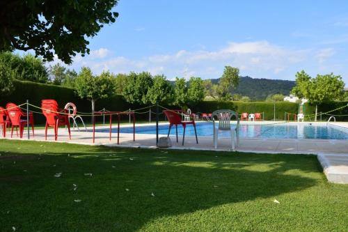 a swimming pool with red chairs next to a swimming pool at Casa Carbonero in Lascuarre