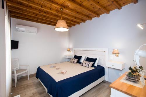 a bedroom with a bed with a blue and white comforter at Filoxenia Apartments in Ornos