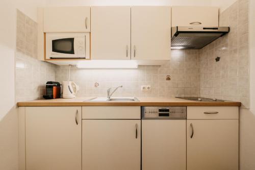 a kitchen with white cabinets and a sink at Landhaus Rohrmoser in Werfenweng