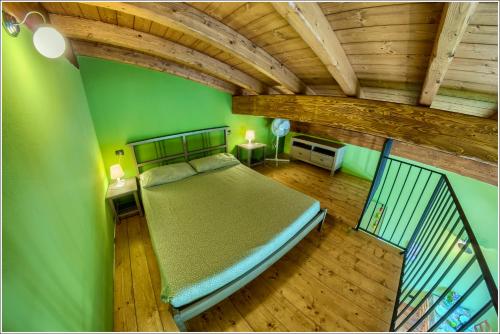 a bedroom with a bed with green walls and wooden floors at Fantastica Casa Poppo in Bellano