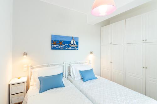 two beds in a bedroom with white cabinets and blue pillows at Notos Apartments Xerokambos 3 in Xerokampos