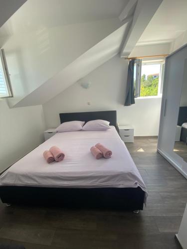 a bedroom with a bed with two pink pillows on it at GUESTHOUSE RUZA SOBRA apartments in the attic of the house in Sobra