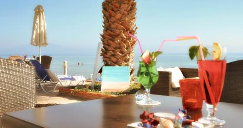 a table with drinks on it with a view of the beach at Belussi Beach Hotel & Suites in Kipseli