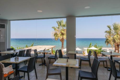 a restaurant with tables and chairs and a view of the ocean at Belussi Beach Hotel & Suites in Kipseli