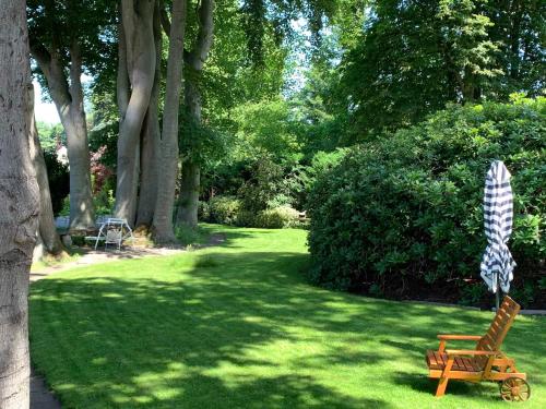 einen Hof mit einem Stuhl und einem Regenschirm im Gras in der Unterkunft Ferienwohnung Alte Fehnapotheke, 95144 in Rhauderfehn