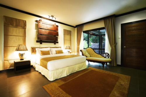a bedroom with a bed and a chair and a window at Felda Residence Hot Springs in Sungkai