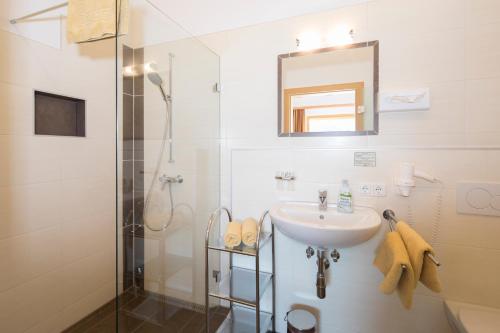 a white bathroom with a sink and a shower at Hotel & Alpengasthof Pinzgerhof in Reith im Alpbachtal