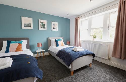 a bedroom with two beds and a blue wall at Listers Nest in Exley
