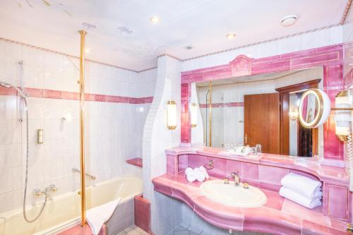 a pink bathroom with a tub and a sink at Der Lärchenhof in Erpfendorf