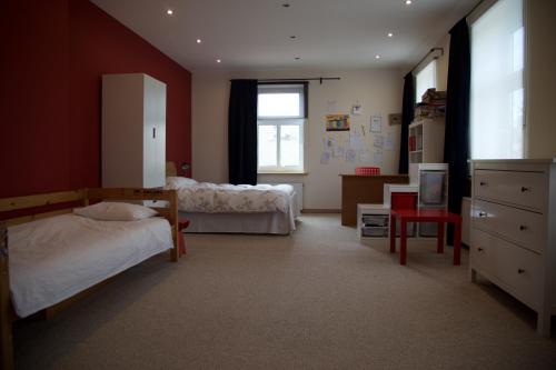 a bedroom with two beds and a red wall at Altribute Studio w Sauna Secure Parking wifi 90mbs in Liepāja