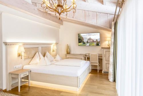 a bedroom with a white bed and a desk at Der Lärchenhof in Erpfendorf