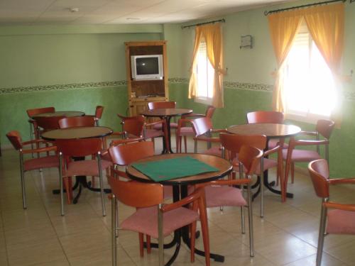 Habitación con mesas, sillas y TV. en Hotel Gil en Montanejos