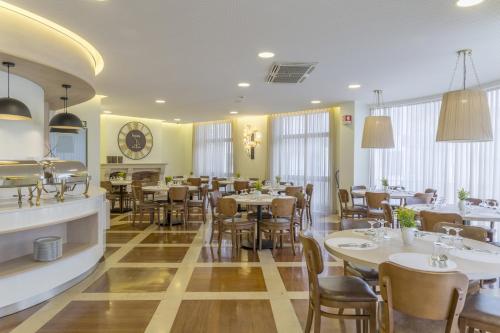 a restaurant with tables and chairs and a clock on the wall at Hotel Cinquentenario & Conference Center in Fátima