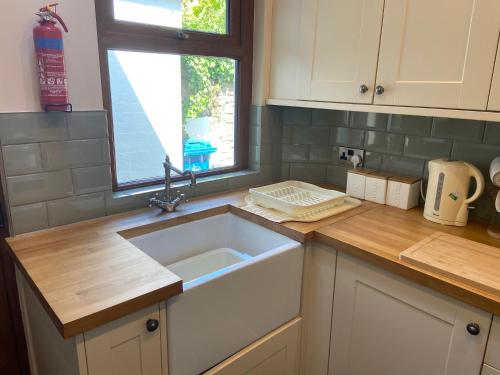 eine Küchentheke mit einem Waschbecken und einem Fenster in der Unterkunft Nab View Cottage in Whalley