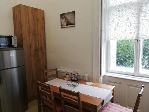 a kitchen with a table and a refrigerator and a window at GOLD 2 Apartman in Sopron