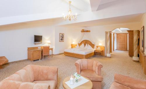 a hotel room with a bed and a couch and chairs at Der Lärchenhof in Erpfendorf