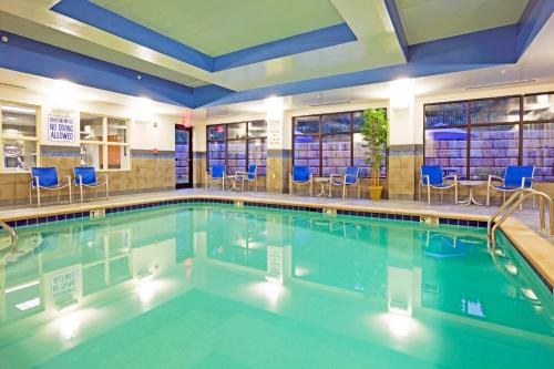 a pool in a hotel with blue chairs and tables at Holiday Inn Express & Suites Knoxville-Farragut by IHG in Knoxville