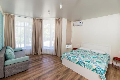 ein Schlafzimmer mit einem Bett, einem Sofa und einem Fenster in der Unterkunft Апартаменты "Гамма ДеЛюкс" in Olginka