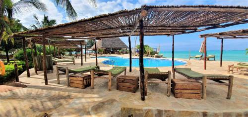 a resort with a pool and chairs and a umbrella at Reef & Beach Resort - Spa Jambiani in Jambiani