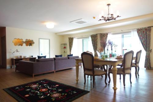 a dining room and living room with a table and a couch at Baan Rub Lom by Jane in Pak Chong