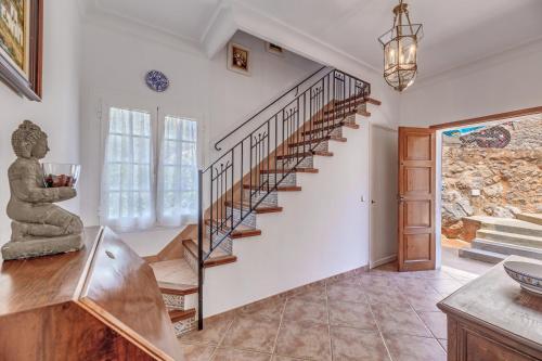 a spiral staircase in a living room with a stone wall at Casa Paqui in Port de Soller
