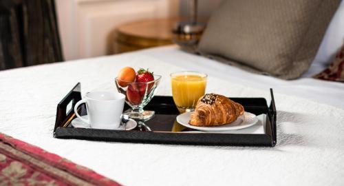 Una bandeja con alimentos y bebidas para el desayuno sobre una cama. en AQA Palace, en Florencia