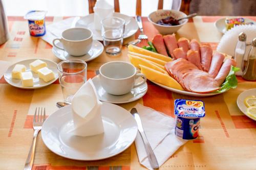 einen Tisch mit Teller mit Lebensmitteln, Tassen und Teller mit Lebensmitteln in der Unterkunft Hostel Rest in Krakau