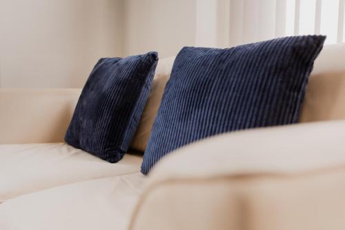 a white couch with two blue pillows on it at PLATFORM City Studio with Parking in Hull