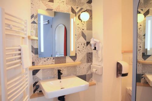 a bathroom with a sink and a mirror at Logis Hôtels- Hôtel Marguerite d'Anjou Angers château in Angers
