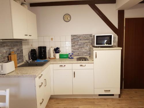 a kitchen with white cabinets and a microwave at Ferienwohnung Siebmann in Neuruppin