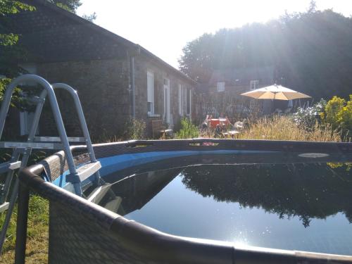 a swimming pool with an umbrella next to a house at Les Gîtes du Château de Passillé in Parigné