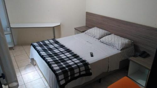 a bedroom with a bed with a black and white blanket at Hotel Vilamoura in Sao Paulo