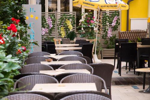 une salle à manger avec des tables, des chaises et des fleurs dans l'établissement Hotel Caraibi, à Rimini