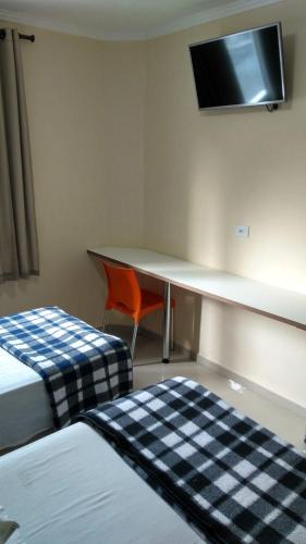 a room with two beds and a desk and a chair at Hotel Vilamoura in Sao Paulo
