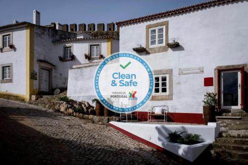 una señal para una señal limpia y segura frente a un edificio en Lugares Com História, en Óbidos