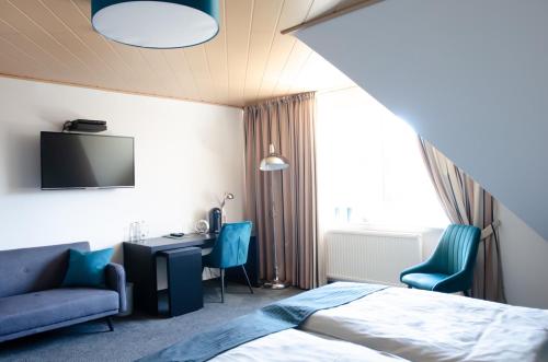 Habitación de hotel con cama, escritorio y TV. en Hotel am Feldmarksee, en Sassenberg