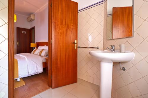 łazienka z umywalką oraz sypialnia z łóżkiem w obiekcie Dolce Vianna - City Centre Rooms w mieście Viana do Castelo