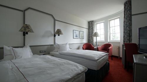 a hotel room with two beds and a chair at Landhaus Alpinia in Berlin