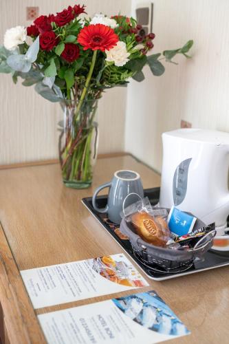 une table avec un vase de fleurs et une assiette de nourriture dans l'établissement Contact Hôtel Limoges - HOTEL DES DEUX MOULINS, à Limoges