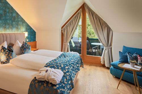 a bedroom with a bed and a couch and a window at Hotel Christina - Ihr kleinstes 4* Hotel am Achensee in Pertisau