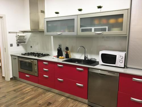 a kitchen with red cabinets and a microwave at Apartamento da Seara "Lamego" in Lamego