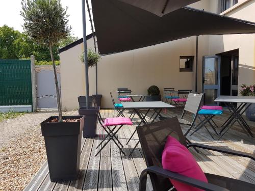 a patio with tables and chairs and an umbrella at Kyriad Hôtel La Fleche in La Flèche