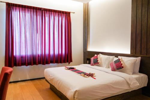 a bedroom with a large bed with a red window at Risasinee Spa & Resort in Nan