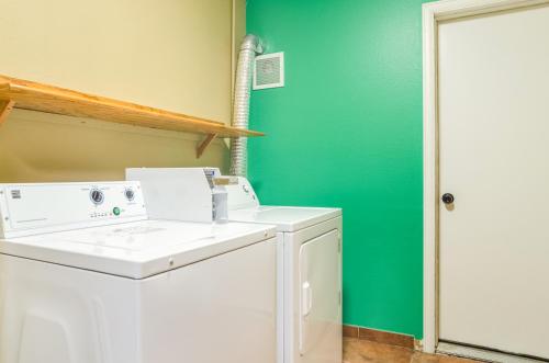 uma máquina de lavar e secar roupa numa lavandaria com uma parede verde em Cheyenne Guest Inn em Cheyenne