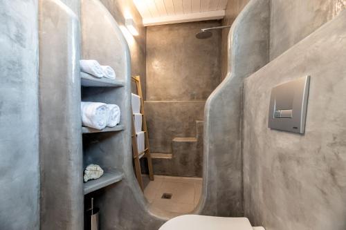 a bathroom with a toilet and a shower with towels at Blue Mare Villas in Naousa
